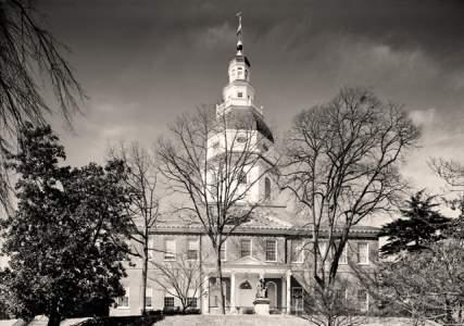 black and white photo of Maryland State House, trees in foreground, clear sky